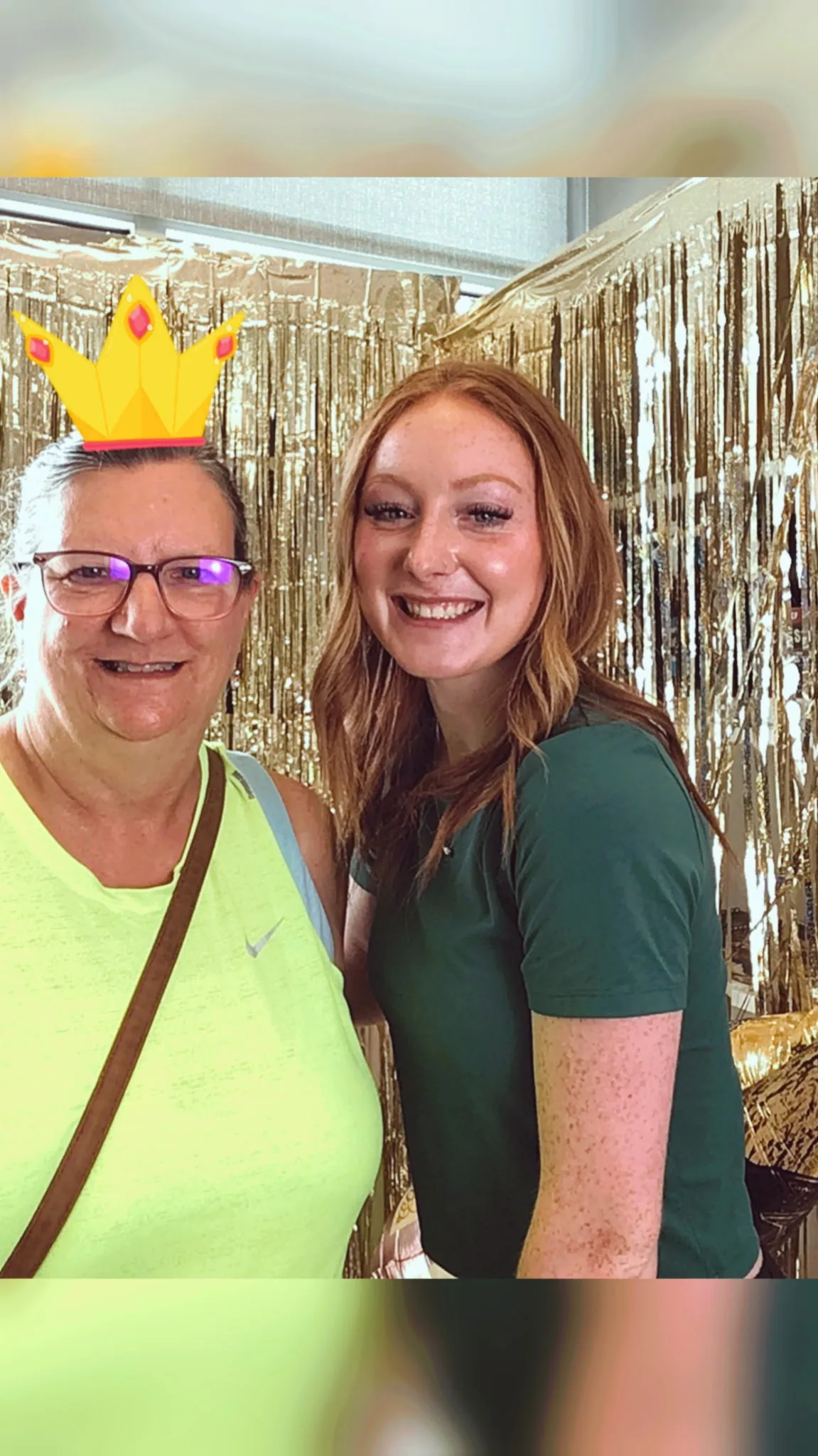 A guest wearing a party crown posing with a team member at the photo backdrop