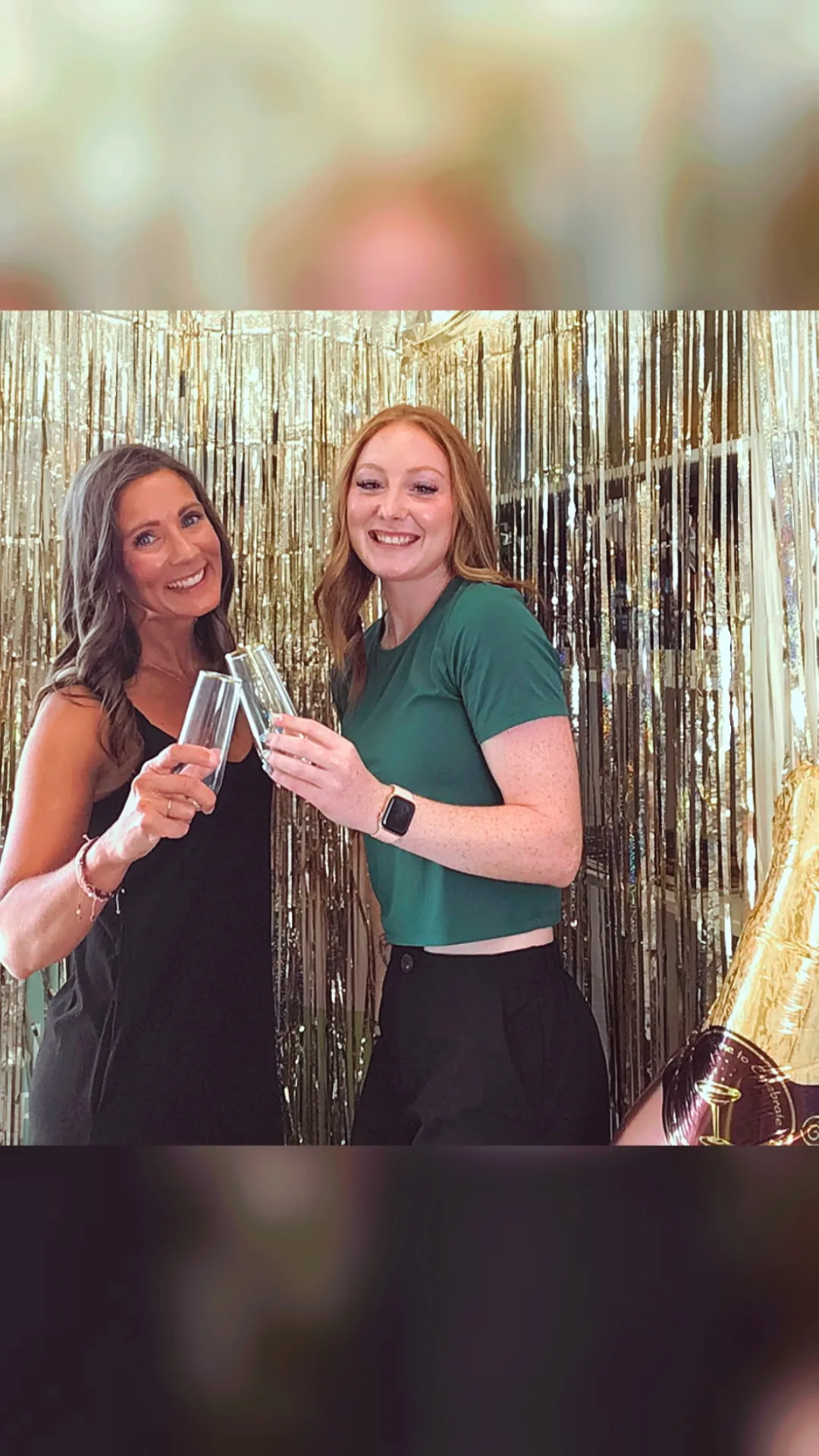 Two smiling guests in front of the gold fringe backdrop