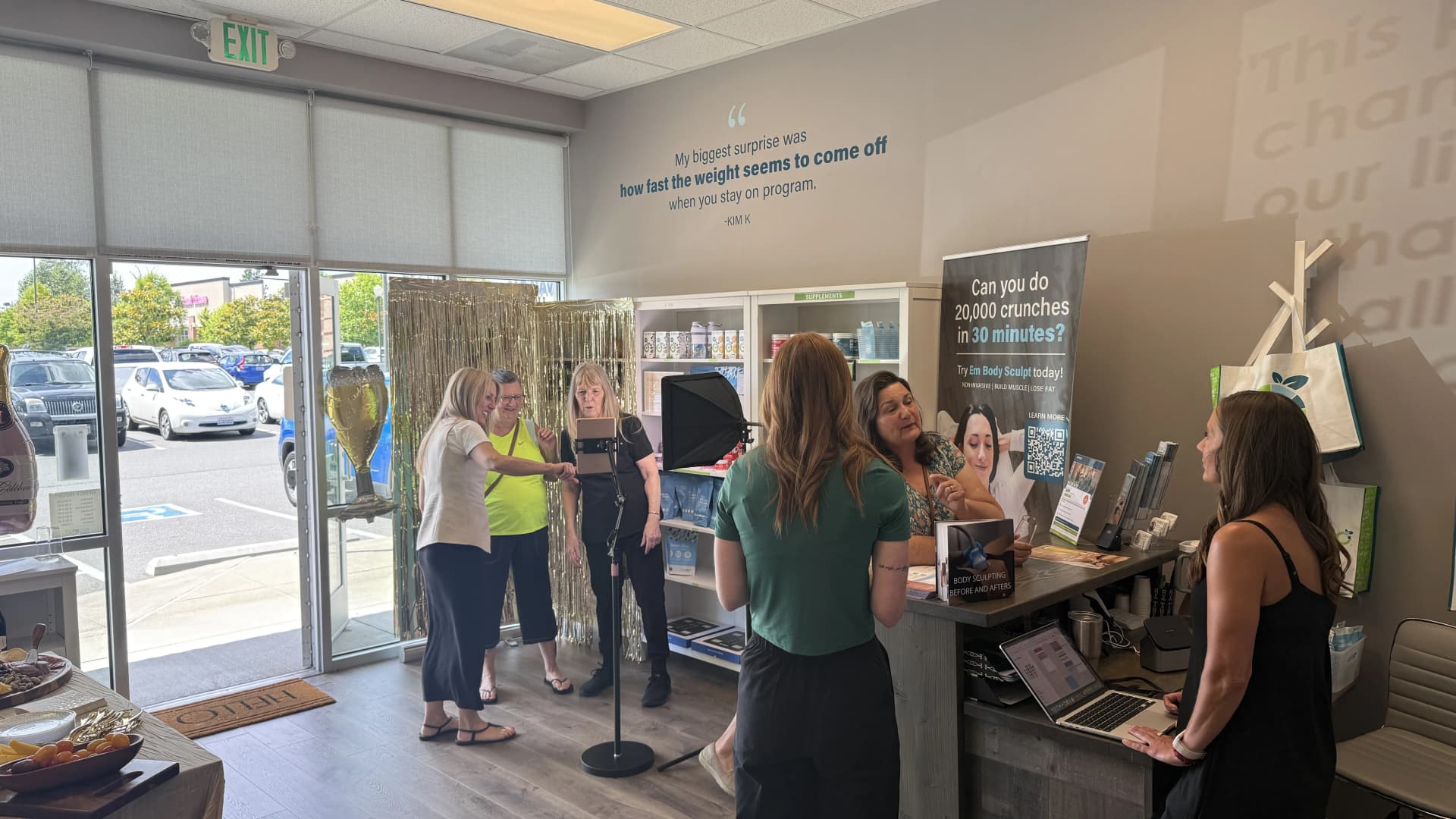Guests mingling in the clinic during a Sip & Sculpt event, with the photo station and snack table set up